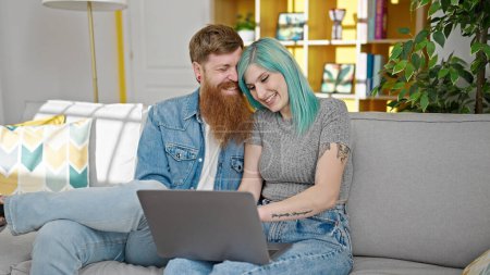 Photo for Man and woman couple sitting on sofa using laptop at home - Royalty Free Image