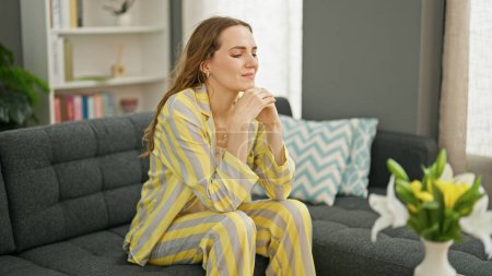Foto de Mujer rubia joven sentada en el sofá con expresión de ansiedad en casa - Imagen libre de derechos