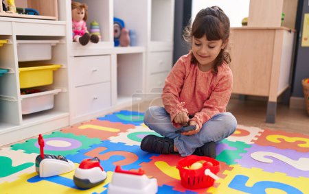 Photo for Adorable hispanic girl playing supermarket game sitting on floor at kindergarten - Royalty Free Image