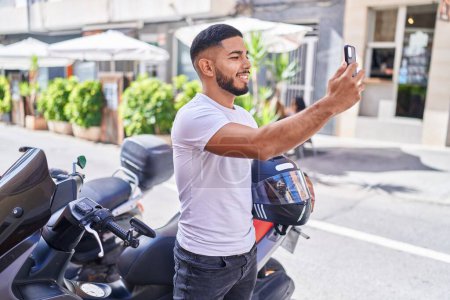 Téléchargez les photos : Young latin man make selfie by smartphone standing by motorbike at street - en image libre de droit