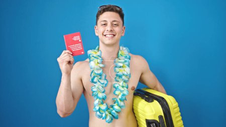 Téléchargez les photos : Jeune homme hispanique touriste tenant passeport suisse et valise sur fond bleu isolé - en image libre de droit