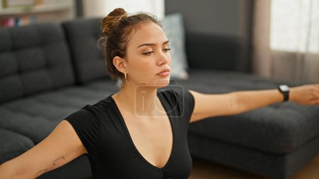 Téléchargez les photos : Jeune belle femme hispanique portant des vêtements de sport assis sur le sol respirant à la maison - en image libre de droit