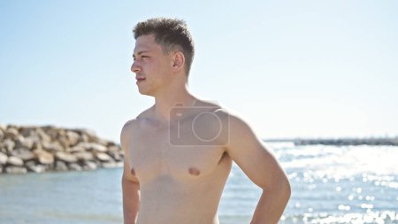 Foto de Joven turista hispano de pie con expresión relajada a orillas del mar - Imagen libre de derechos