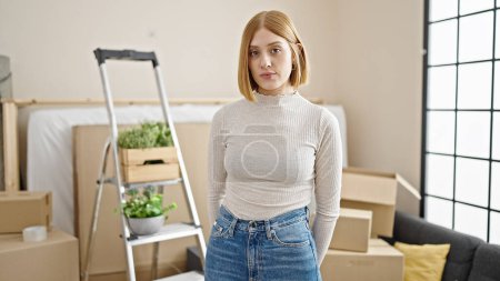 Photo for Young blonde woman standing with relaxed expression at new home - Royalty Free Image