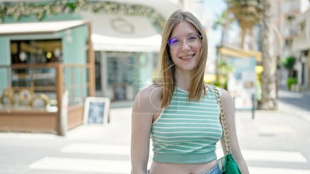Téléchargez les photos : Jeune femme blonde souriante confiante debout à la terrasse du café - en image libre de droit