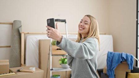 Foto de Mujer rubia joven hacer selfie por teléfono inteligente de pie en el nuevo hogar - Imagen libre de derechos