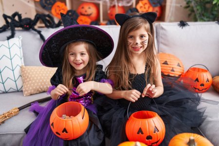 Foto de Adorables chicas que tienen fiesta de Halloween celebración de cesta de calabaza en casa - Imagen libre de derechos