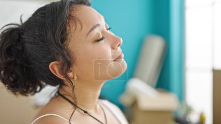 Téléchargez les photos : Jeune belle femme hispanique respirant avec les yeux fermés à la nouvelle maison - en image libre de droit