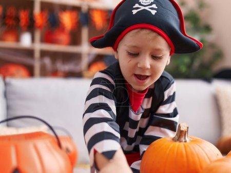 Foto de Adorable chico caucásico usando traje de pirata teniendo fiesta de Halloween en casa - Imagen libre de derechos