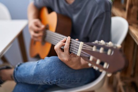 Photo for Young caucasian man playing classical guitar at home - Royalty Free Image