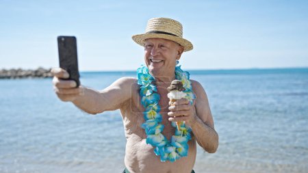 Foto de Senior hombre de pelo gris turista celebración de helados hacer selfie por teléfono inteligente en la playa - Imagen libre de derechos