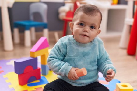 Téléchargez les photos : Adorable hispanic baby playing with construction blocks sitting on floor at kindergarten - en image libre de droit