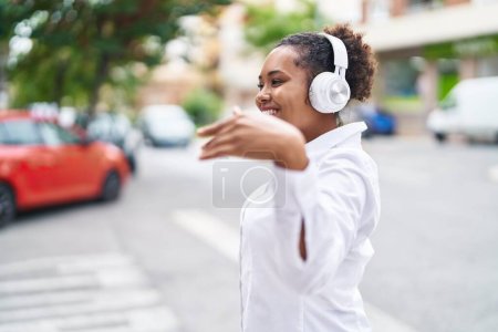 Téléchargez les photos : Femme afro-américaine écoutant de la musique et dansant dans la rue - en image libre de droit