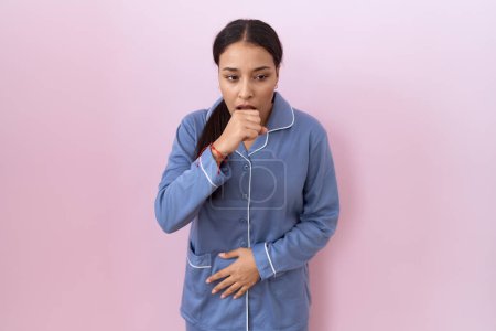 Foto de Mujer árabe joven que usa pijama azul sintiéndose mal y tosiendo como síntoma de resfriado o bronquitis. concepto de atención sanitaria. - Imagen libre de derechos