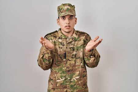 Photo for Young arab man wearing camouflage army uniform clueless and confused with open arms, no idea concept. - Royalty Free Image