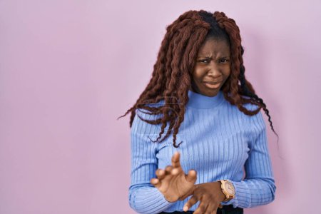 Photo for African woman standing over pink background disgusted expression, displeased and fearful doing disgust face because aversion reaction. - Royalty Free Image