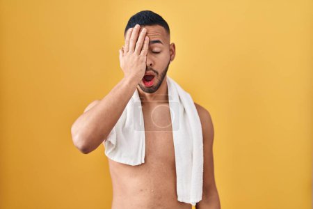 Téléchargez les photos : Jeune homme hispanique debout torse nu avec serviette bâillant fatigué couvrant la moitié du visage, l'œil et la bouche avec la main. mal au visage dans la douleur. - en image libre de droit
