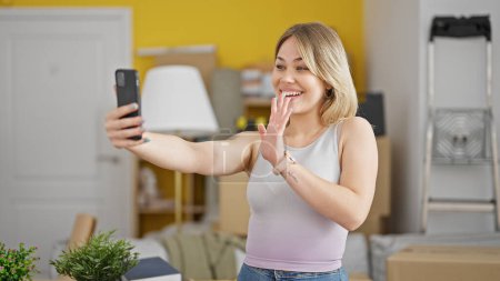 Photo for Young blonde woman having video call smiling at new home - Royalty Free Image