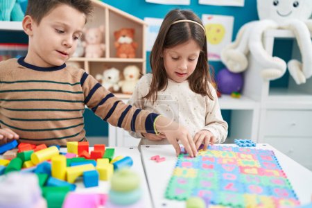 Photo for Adorable boy and girl playing with construction blocks and vocabulary puzzle at kindergarten - Royalty Free Image