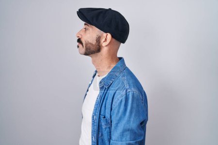 Photo for Hispanic man with beard standing over isolated background looking to side, relax profile pose with natural face and confident smile. - Royalty Free Image