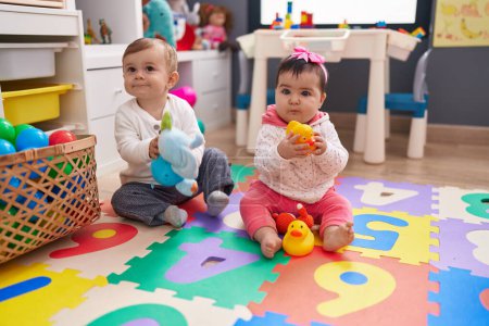 Photo for Adorable boy and girl playing with balls sitting on floor at kindergarten - Royalty Free Image