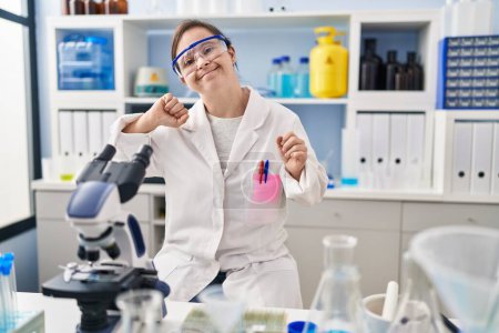Photo for Hispanic girl with down syndrome working at scientist laboratory dancing happy and cheerful, smiling moving casual and confident listening to music - Royalty Free Image