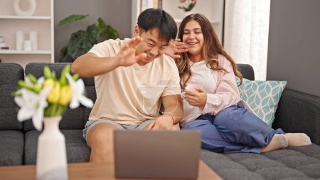 Photo for Man and woman couple sitting on sofa having video call drinking coffee at home - Royalty Free Image