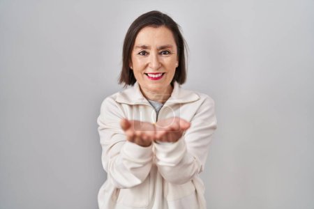 Photo for Middle age hispanic woman standing over isolated background smiling with hands palms together receiving or giving gesture. hold and protection - Royalty Free Image