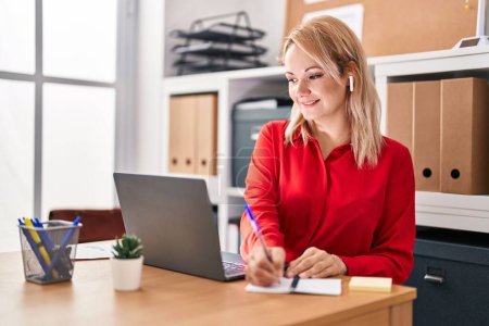 Téléchargez les photos : Jeune femme blonde travailleur d'affaires en utilisant l'écriture d'ordinateur portable sur ordinateur portable au bureau - en image libre de droit