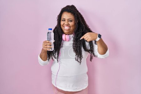 Photo for Plus size hispanic woman wearing sportswear and headphones looking confident with smile on face, pointing oneself with fingers proud and happy. - Royalty Free Image