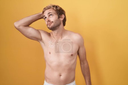 Téléchargez les photos : Homme caucasien debout torse nu portant écran solaire souriant confiant toucher les cheveux avec geste de la main vers le haut, posant attrayant et à la mode - en image libre de droit