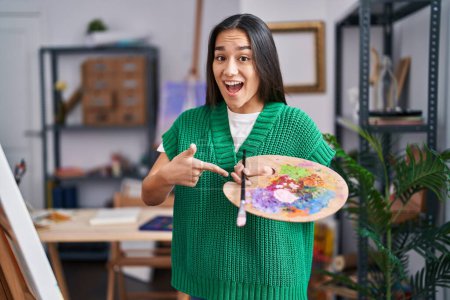 Photo for Young south asian woman holding painter palette smiling happy pointing with hand and finger - Royalty Free Image