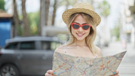 Photo for Young blonde woman tourist looking city map smiling at street - Royalty Free Image