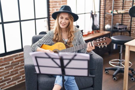 Téléchargez les photos : Jeune musicienne blonde jouant de la guitare classique au studio de musique - en image libre de droit