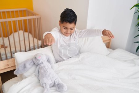 Photo for Adorable hispanic boy somnambulist sitting on bed at bedroom - Royalty Free Image