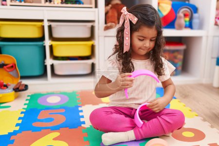 Photo for Adorable hispanic girl playing with construction blocks sitting on floor at kindergarten - Royalty Free Image