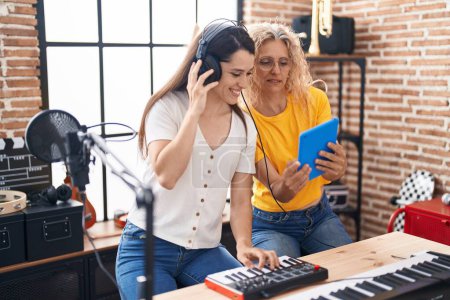 Photo for Two women musicians composing song using keyboard and touchpad at music studio - Royalty Free Image
