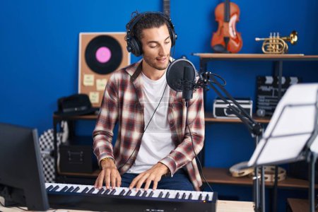 Téléchargez les photos : Jeune homme hispanique musicien chantant une chanson jouant du piano au studio de musique - en image libre de droit