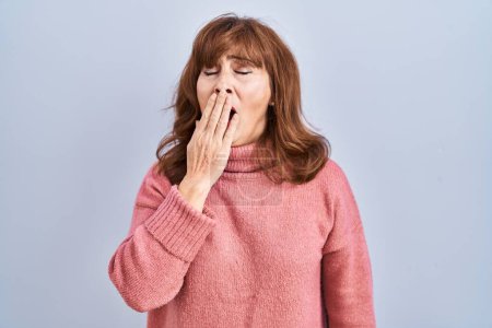 Photo for Middle age hispanic woman standing over isolated background bored yawning tired covering mouth with hand. restless and sleepiness. - Royalty Free Image