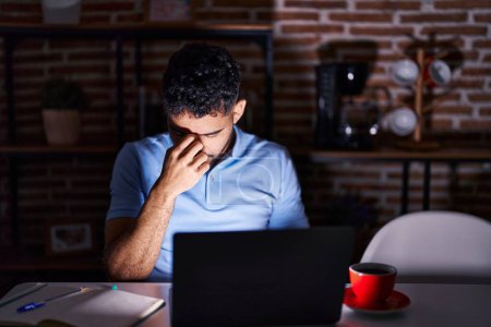Photo for Hispanic man with beard using laptop at night tired rubbing nose and eyes feeling fatigue and headache. stress and frustration concept. - Royalty Free Image