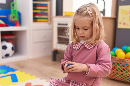 Photo for Adorable blonde girl playing with toys sitting on floor at kindergarten - Royalty Free Image