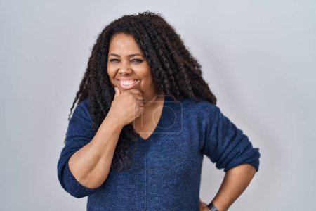 Photo for Plus size hispanic woman standing over white background looking confident at the camera with smile with crossed arms and hand raised on chin. thinking positive. - Royalty Free Image