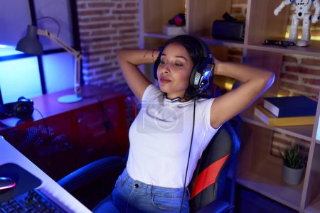 Téléchargez les photos : Jeune femme arabe streamer détendu avec les mains sur la tête à la salle de jeux - en image libre de droit