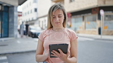Foto de Young blonde woman using touchpad at street - Imagen libre de derechos
