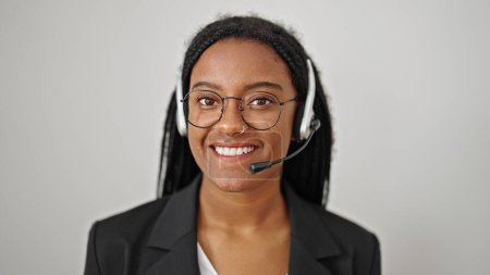 Téléchargez les photos : Femme afro-américaine agent du centre d'appel souriant confiant parlant sur fond blanc isolé - en image libre de droit