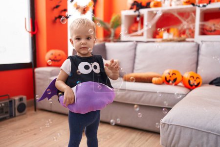 Foto de Adorable chico caucásico con disfraz de halloween jugando con burbujas de jabón en casa - Imagen libre de derechos