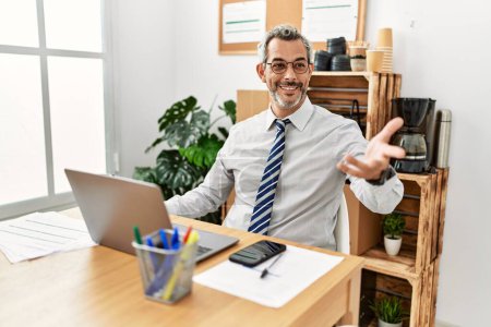 Téléchargez les photos : Homme d'affaires aux cheveux gris d'âge moyen utilisant un ordinateur portable parlant au bureau - en image libre de droit