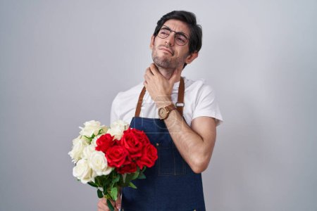 Téléchargez les photos : Jeune homme hispanique tenant un bouquet de roses blanches et rouges touchant le cou douloureux, mal de gorge pour la grippe, la motte et l'infection - en image libre de droit