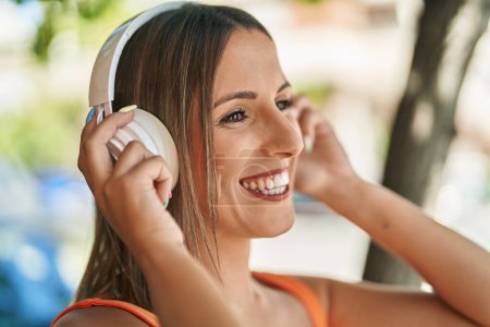 Téléchargez les photos : Jeune belle femme hispanique souriant confiant écouter de la musique dans la rue - en image libre de droit