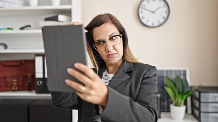 Téléchargez les photos : Moyen-Orient femme d'affaires travailleur peignage cheveux avec la main regardant sur touchpad au bureau - en image libre de droit
